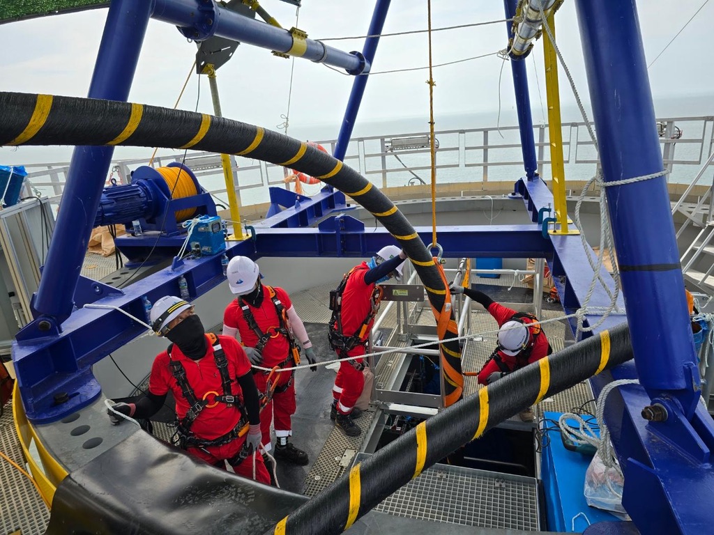 Crew handling the cable through the turn-over hoop